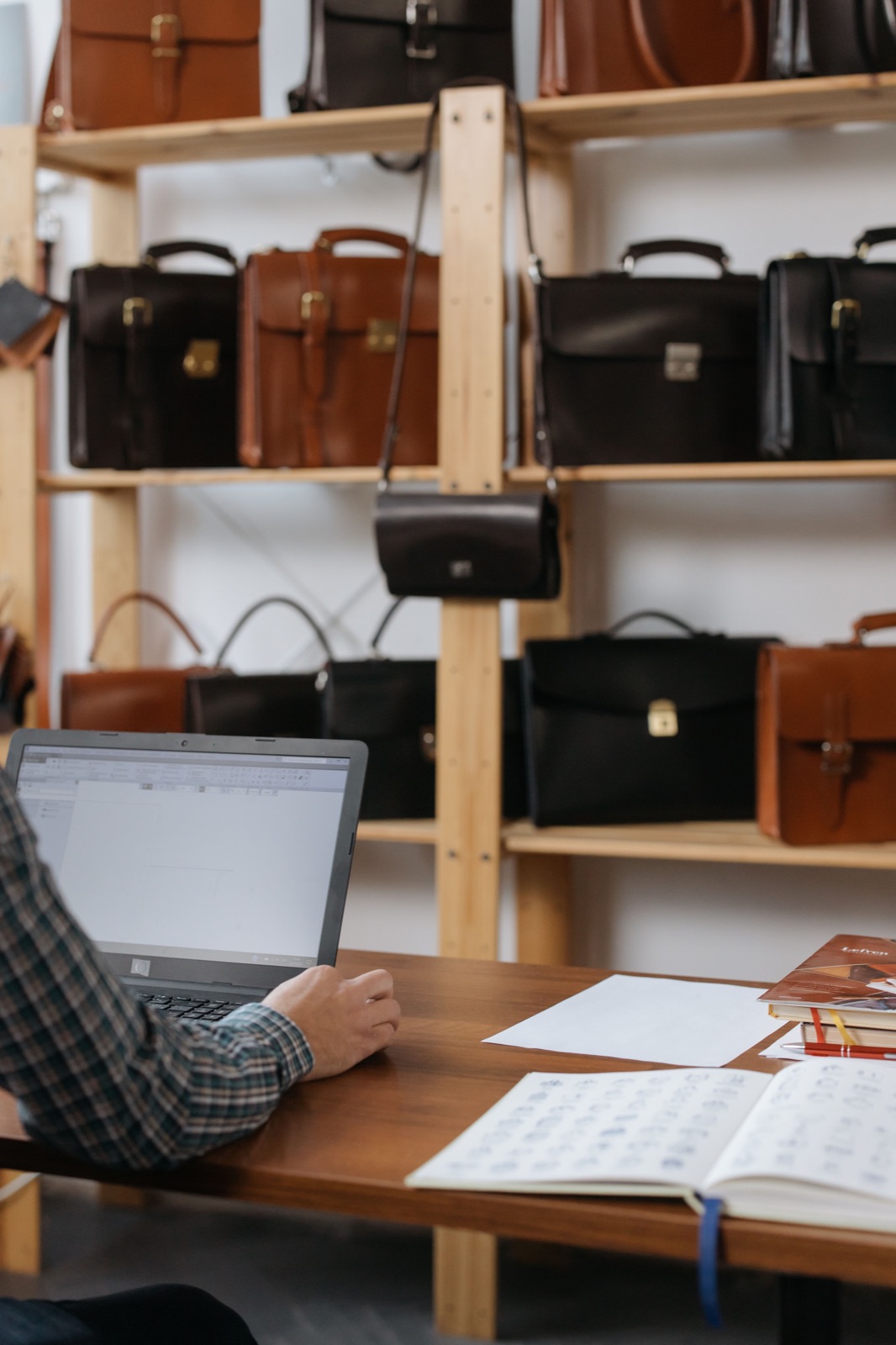 A person working on a laptop in a leather-goods shop